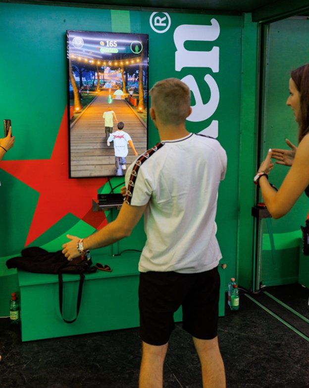 A fan steering the runner with his body, the festival world on the screen in front of him