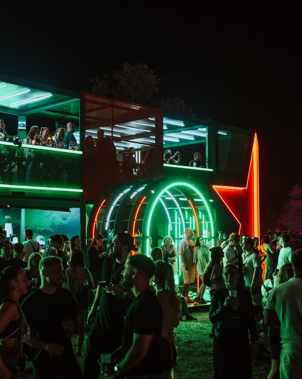 The Heineken House lit up at night, neon arches and the red star glowing